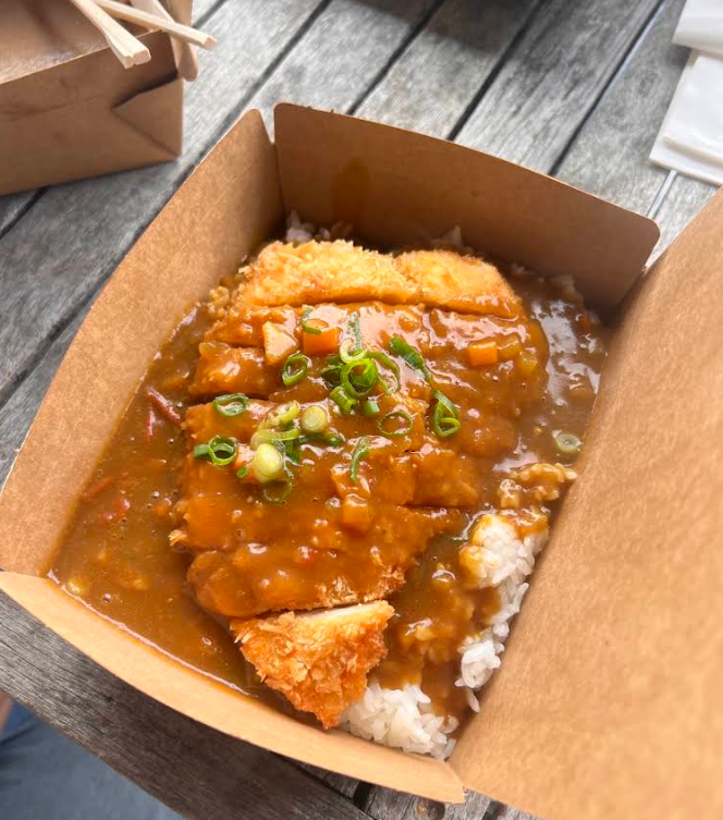 Crumbed chicken curry over rice in a takeaway box
